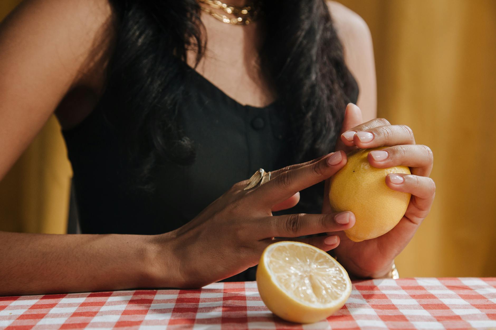 A yellow silicone lemon clitoral vibrator surrounded by peeled lemons on a bright yellow background