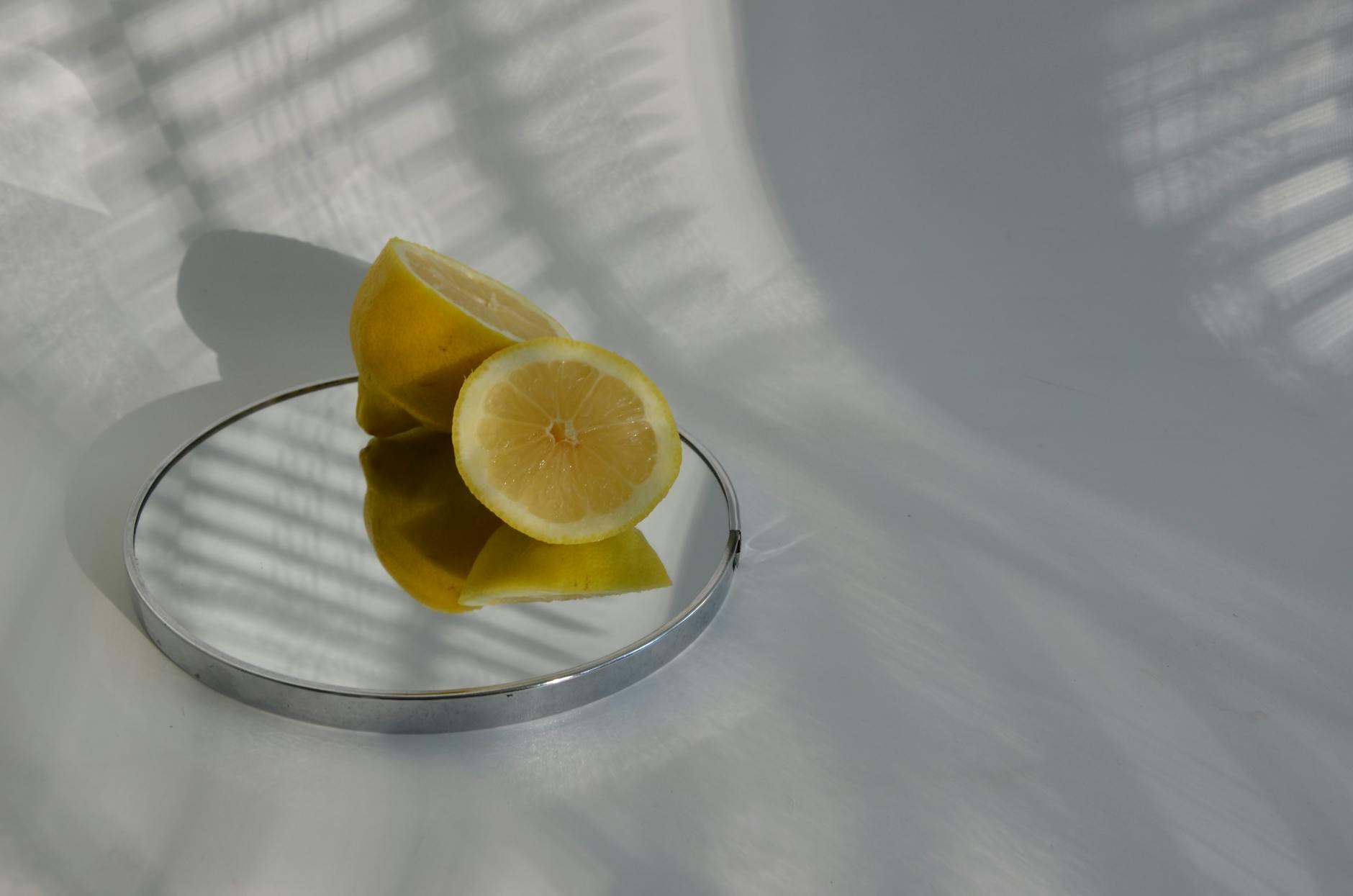 Hand holding a fresh lemon on a soft pink background, symbolizing sensitivity and care