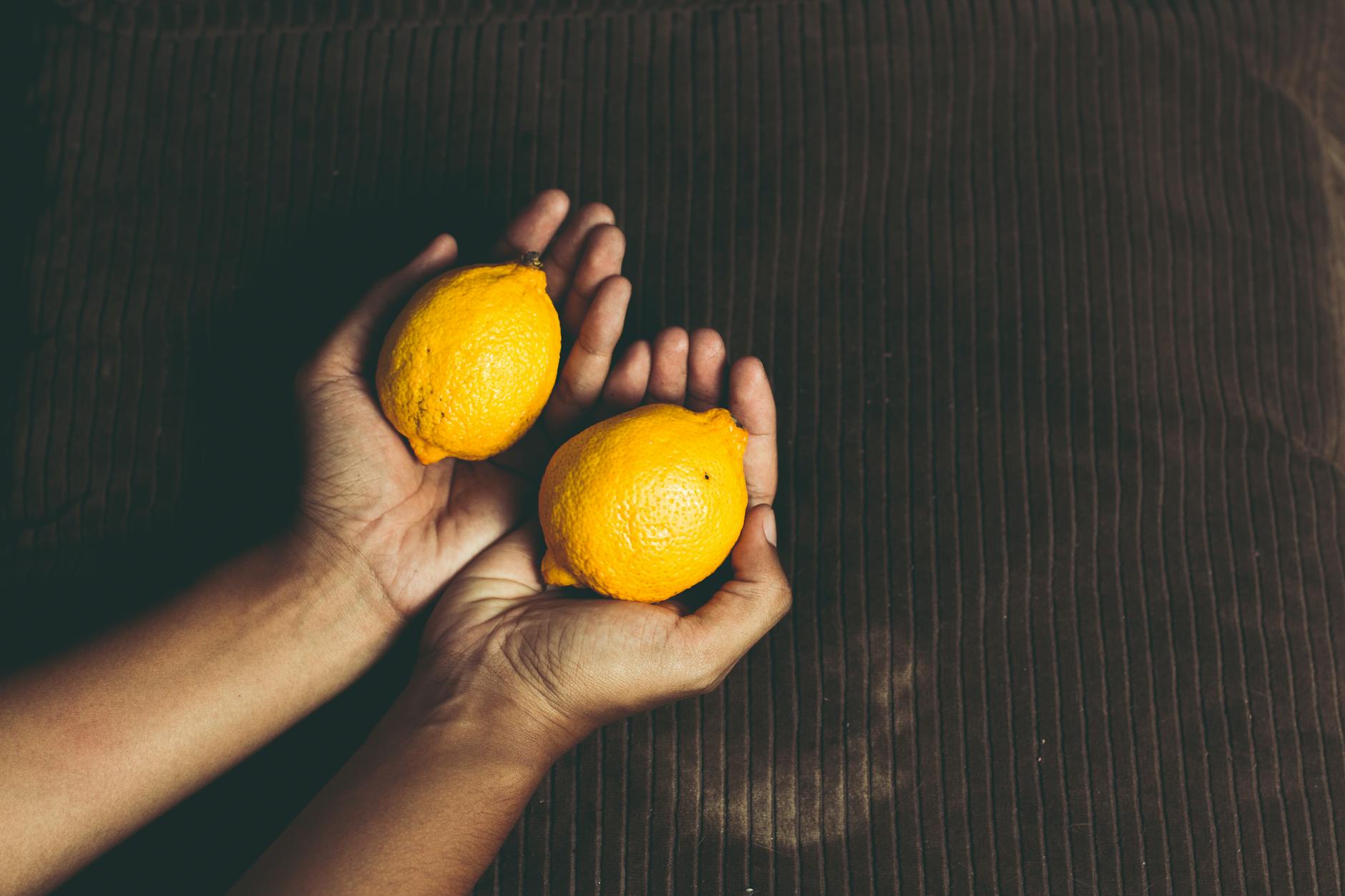 A hand holding a modern orange vibrator against a purple backdrop, symbolizing intimate self-care