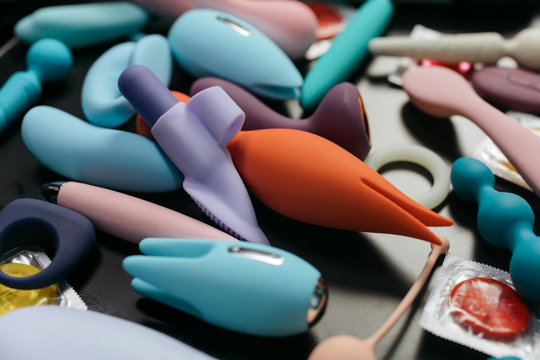 An array of vibrant adult toys including vibrators and rings in a close-up view.