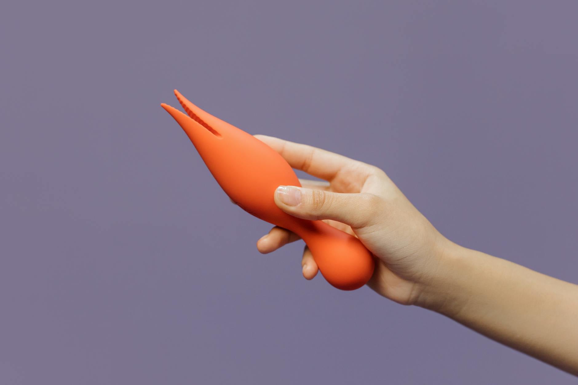 A hand holding a lemon vibrator against a minimalistic purple backdrop, showcasing modern sensuality.