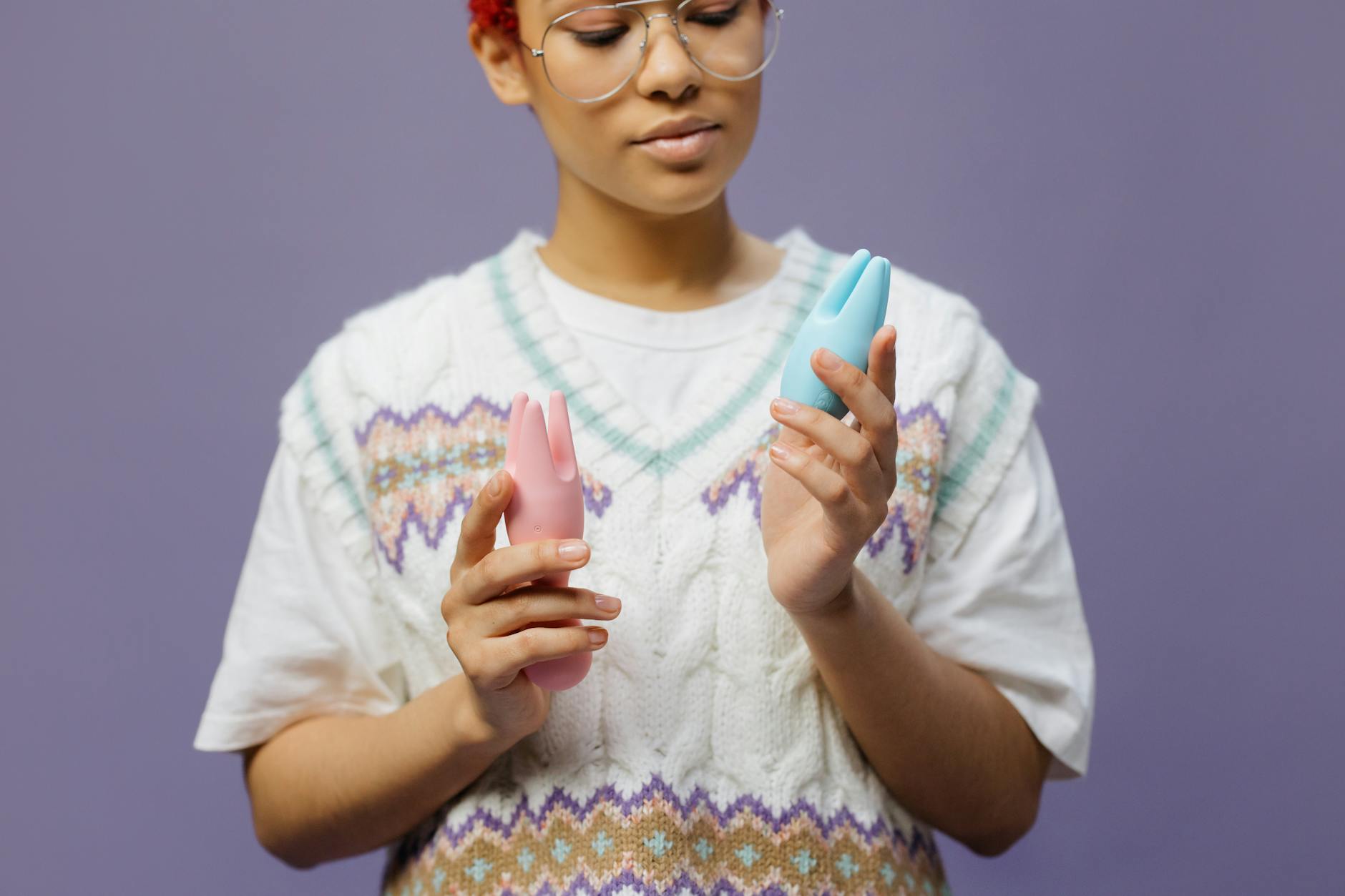 A couple standing together indoors, holding a blue vibrator and exploring intimacy together.