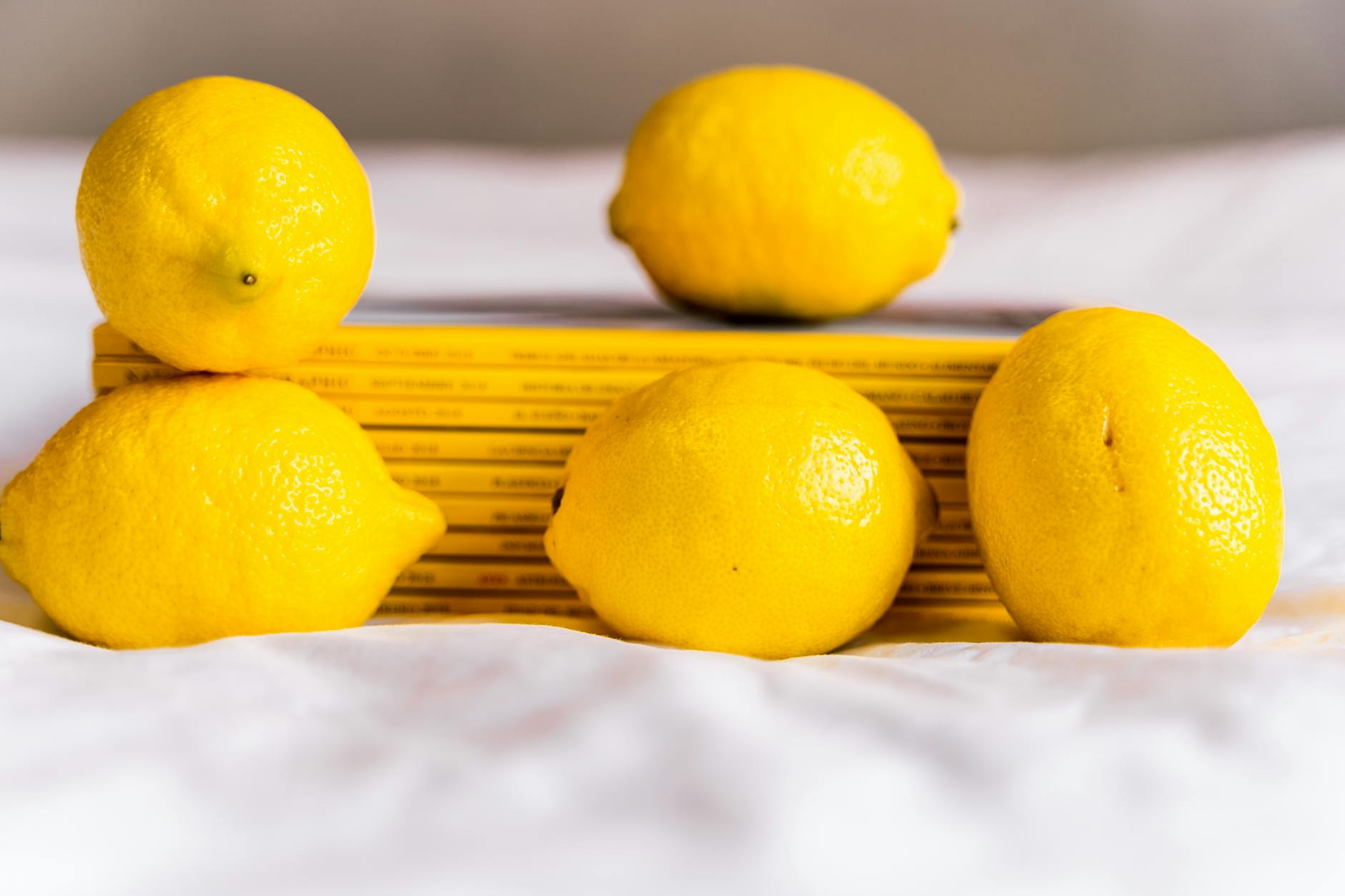 Fresh lemons with stacked books on white fabric, symbolizing renewal and intimacy in long-term relationships